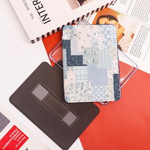 May include: A rectangular case with a patchwork design in shades of blue and white, featuring floral and plaid patterns. A brown case with a gray strap is also visible, along with a clear plastic case and a magazine.