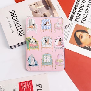 Peut inclure: Étui de téléphone rose avec un motif répété de chiens assis dans des chaises ornées. Les chiens portent des tenues différentes et sont dans des poses variées. Le fond est de couleur rose clair.