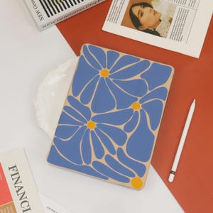 May include: A laptop sleeve featuring a floral design. The sleeve is beige with blue and yellow flowers.