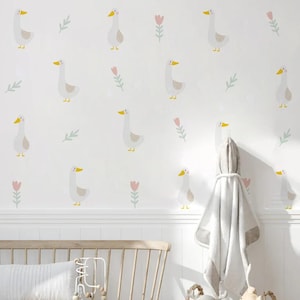 May include: A white wall with a repeating pattern of light gray geese and pink flowers. The wall is in a room with white trim and a white wooden bench with a gray throw blanket hanging on a hook.