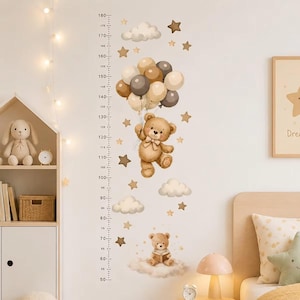 May include: A wall decal height chart featuring a brown teddy bear holding a bunch of beige, brown, and white balloons, a smaller teddy bear sitting on a cloud, and scattered stars and clouds with measurement markings from 50 to 180 cm.