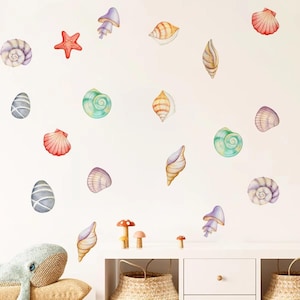 Op de afbeelding: Waterverf muurstickers met verschillende schelpen, een zeester en paddenstoelontwerpen in tinten rood, paars, groen en geel. De stickers zijn gerangschikt op een witte achtergrond, waardoor een grillige, oceaan-thema esthetiek ontstaat.