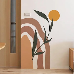 Puede incluir: Un mural con un diseño abstracto en tonos tierra. El mural presenta formas curvas en tonos marrón y beige, un círculo amarillo y una silueta de planta verde oscuro. El diseño está en una pared blanca.