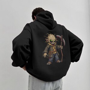 Dark horror hoodie featuring a chibi scarecrow reaper with glowing green eyes and a bloody scythe. This high-resolution PNG design is perfect for sublimation, gothic apparel, horror-themed fashion, digital prints, and Halloween merch. The eerie aesthetic makes it ideal for horror lovers, gothic streetwear fans, and collectors of creepy designs.