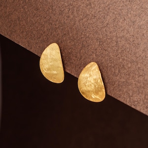 Peut inclure: Une paire de boucles d'oreilles dorées avec une finition texturée martelée. Les boucles d'oreilles sont en forme de goutte d'eau.