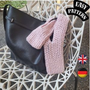 Könnte beinhalten: Eine schwarze Lederhandtasche mit Schulterriemen liegt auf einem weißen Stuhl. Ein hellrosa gehäkelter Artikel ist über die Tasche drapiert. Das Bild enthält den Text "EASY PATTERN".