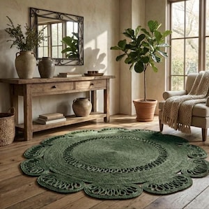 May include: A green, round jute rug with a floral design sits on a wooden floor. The rug is the focal point of a room with a wooden console table, a mirror, and a potted plant. A woven basket and a beige armchair are also visible.