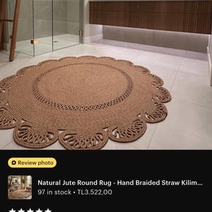 May include: A round, natural jute rug with a braided design. The rug has a scalloped edge and is approximately 5 feet in diameter. It is placed on a tiled floor in a bathroom setting.