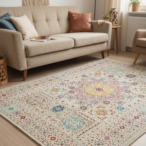 Puede incluir: Alfombra beige con un patrón detallado y colorido. La alfombra presenta un diseño de medallón central en amarillo y rosa, rodeado de formas geométricas en azul, rojo y morado. La alfombra está en un salón.