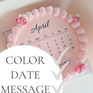 May include: A pink cake with a calendar design for April, decorated with pink frosting swirls and small rose accents. The cake is in a box, with the words "COLOR DATE MESSAGE" overlaid on the image.