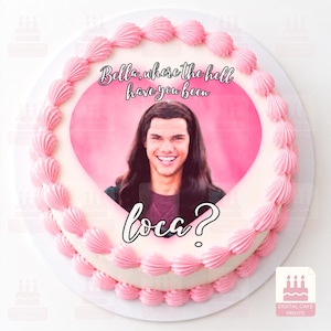 Könnte beinhalten: Ein runder Kuchen mit einem rosafarbenen, herzförmigen essbaren Bild einer Person mit langem dunklem Haar. Der Text lautet, Bella, where the hell have you been loca? Der Kuchen ist mit einem Rand aus rosafarbenen, aufgespritzten Glasurtupfen verziert.