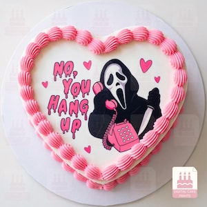 Puede incluir: Un pastel en forma de corazón con glaseado blanco y un borde rosa. La parte superior presenta un gráfico de una figura enmascarada con túnica negra sosteniendo un teléfono rosa y un cuchillo, con el texto "NO, YOU HANG UP" en letras rosas.