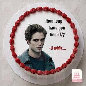 Peut inclure: Un disque décoratif pour gâteau représentant le portrait d'un homme aux cheveux bruns portant une veste grise. Le texte indique, How long have you been 17? - A while.... Le tout est entouré d'une bordure de glaçage rouge en relief.