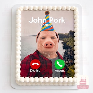 Könnte beinhalten: Ein rechteckiger Kuchen mit weißem Spritzglasur-Rand und einem essbaren Aufdruck eines Schweins mit Partyhut. Das Bild zeigt den Text John Pork is calling sowie rote und grüne Schaltflächen zum Ablehnen oder Annehmen eines Anrufs.
