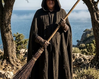 May include: A dark brown hooded cloak made of a textured, heavy fabric, worn over dark clothing. The cloak features a front button closure and reaches down to the shins. Brown leather gloves and brown leather boots complete the ensemble.