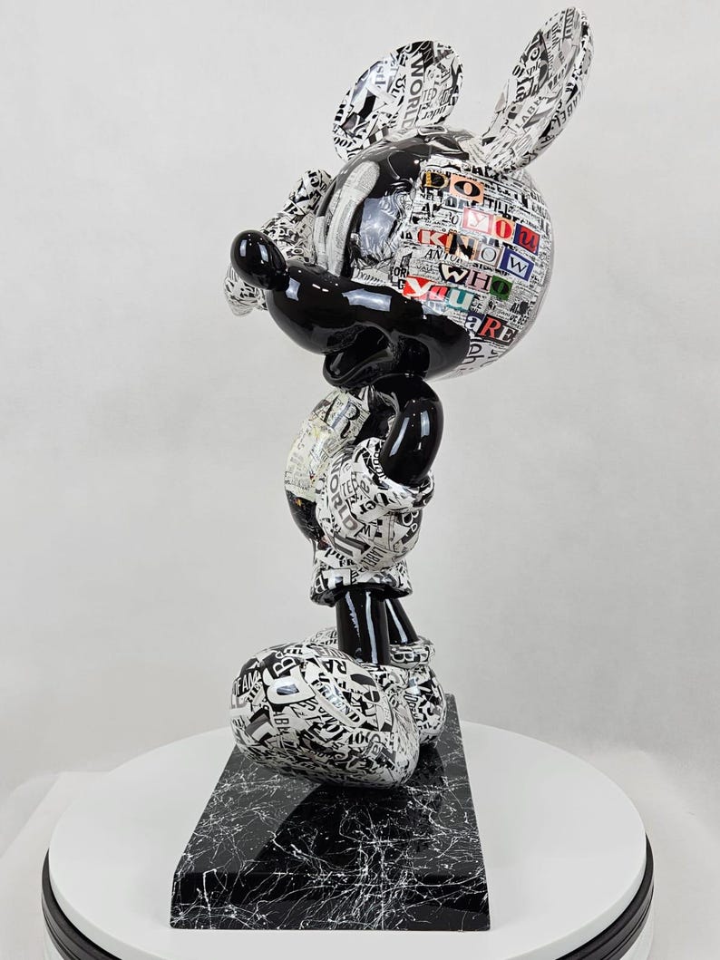 Pode incluir: Figura de Mickey Mouse em preto e branco com um design de impress&atilde;o de jornal. A figura est&aacute; em p&eacute; sobre uma base de m&aacute;rmore preto.