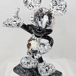 Può includere: Figurina di Mickey Mouse in bianco e nero con una camicia a motivi bianco e nero. La statuetta è in piedi su una base bianca e nera. La statuetta è realizzata in resina ed è alta circa 30 cm.