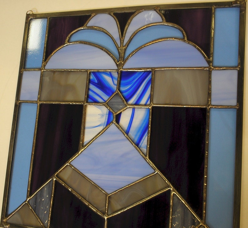 May include: A stained glass window with a geometric design featuring blue, purple, and brown glass pieces.