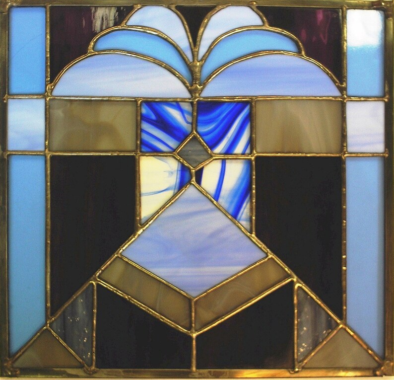 May include: A stained glass window with a geometric design featuring blue, brown, and black glass pieces. The window has a gold frame.