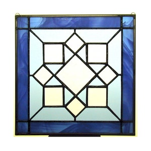 May include: A stained glass window panel with a geometric design featuring a central diamond shape surrounded by smaller squares and diamonds. The glass is a gradient of blue shades.