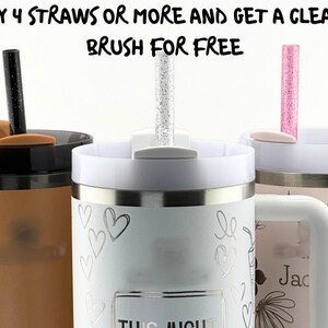 May include: Image features three insulated tumblers with straws. The tumblers are in shades of tan, white, and pink. The white tumbler has heart designs. The text at the top says "BUY 4 STRAWS OR MORE AND GET A CLEANING BRUSH FOR FREE."