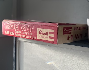 May include: A vintage Revell H-O scale train set box. The red and tan box features the words "TRAIN SET" in large white letters. It includes "power pack & track" and is ready to run. The box is slightly worn, suggesting its age.