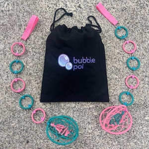 May include: A black drawstring bag with the text bubble poi and a bubble graphic, flanked by two poi sets featuring alternating pink and teal wrapped rings, pink fabric finger loops, and spherical woven cages at the ends of the chains.