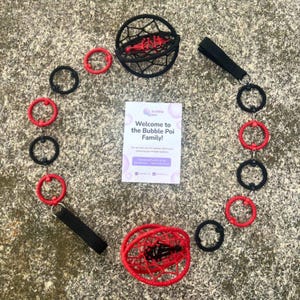 May include: A set of two spherical poi heads in black and red, connected by a chain of alternating black and red rings with black finger loops. A white card in the center reads: Welcome to the Bubble Poi Family! You are now part of a global community.