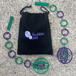 May include: A black drawstring bag with the text bubble poi and a bubble graphic, accompanied by two poi sets. Each set features a green fabric handle, a chain of alternating purple and green rings, and a spherical cage made of woven cord.