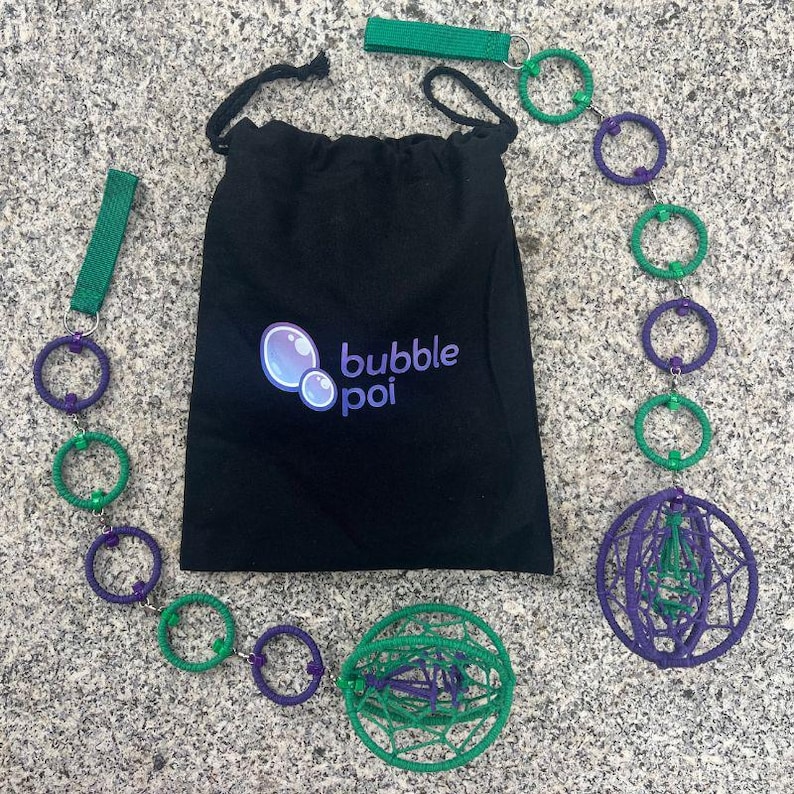 May include: A black drawstring bag with the text bubble poi and a bubble graphic, accompanied by two poi sets. Each set features a green fabric handle, a chain of alternating purple and green rings, and a spherical cage made of woven cord.