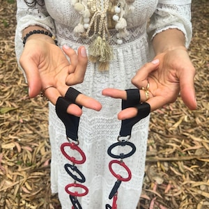 May include: A pair of exercise straps featuring black nylon webbing loops attached to a vertical chain of alternating red and dark blue circular rings. The rings are connected by small metal links, creating a long, flexible, and segmented fitness tool.