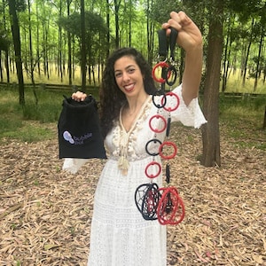 May include: A black drawstring bag with the text bubble poi printed in white, and a set of poi consisting of alternating red and black rings connected by black cords, ending in two spherical structures made of red and black woven cord loops.