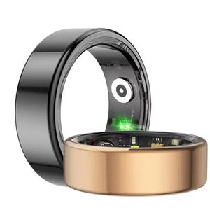 Può includere: Sono mostrati due anelli intelligenti, uno nero e uno dorato. L'anello nero è sullo sfondo e l'anello dorato in primo piano. L'anello dorato ha un circuito stampato visibile all'interno. Una luce verde emana dall'anello dorato.