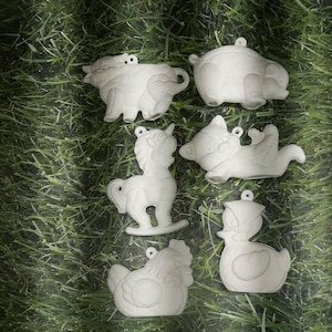 May include: A collection of six unpainted ceramic animal ornaments. The ornaments include a cow, a hippo, a rocking horse, a pig, a chicken, and a duck. Each ornament has a small hole for hanging.