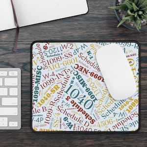 May include: A rectangular mousepad with a black border features a light blue background covered in text related to tax forms, including "1040", "Schedule D", and "1099-MISC". A white computer mouse rests on the pad.