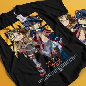 以下が含まれることがあります： 黒いTシャツ。緑色の目と金髪の2人のキャラクターのカラフルなアニメスタイルのイラストが特徴です。「MADE IN ABYSS」という日本語のテキストと単語が含まれています。「LARGE」と書かれたタグ。