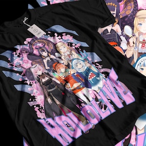 May include: Black t-shirt featuring a colorful graphic of anime characters with the text "HOLOLIVE" in pink. The design includes various female characters with unique outfits and hairstyles, set against a floral and blue background. A white tag is attached.