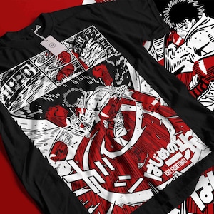 May include: Black t-shirt featuring a manga-style illustration of a boxer in action, with red and white accents. The design includes Japanese text and the English phrase "THE FIGHTING!" A tag is attached to the shirt.