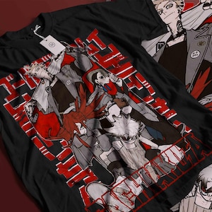 Könnte beinhalten: Schwarzes T-Shirt mit einem rot-weißen Grafikdesign von Anime-Charakteren. Das Design zeigt mehrere Figuren in verschiedenen Posen, begleitet von japanischem Text. Ein weißes Etikett ist am T-Shirt befestigt.
