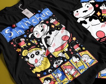 May include: A black t-shirt featuring a colorful graphic print of the character Shin-chan and his dog Shiro. The design includes the text "Shinchan" in blue, along with various small illustrations of the characters in action poses and colorful stars.