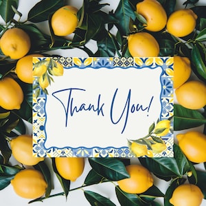 May include: A white card with the words "Thank You!" in blue script, surrounded by a decorative blue and yellow border. The card is set against a backdrop of fresh lemons and green leaves, creating a bright and cheerful design.