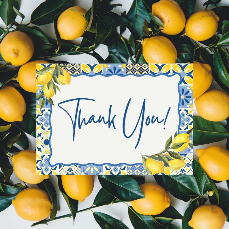 May include: A white card with the words "Thank You!" in blue script, surrounded by a decorative blue and yellow border. The card is set against a backdrop of fresh lemons and green leaves, creating a bright and cheerful design.