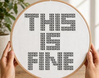 May include: A circular wooden embroidery hoop containing white fabric with black cross-stitched text. The text is arranged to spell out the phrase THIS IS FINE, with each letter composed entirely of the repeated word FUCK in a blocky font style.