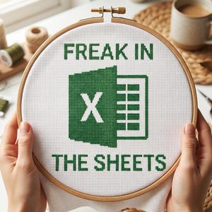 Peut inclure: Un tambour à broder circulaire en bois contenant un tissu blanc avec un motif au point de croix. Le motif présente l'icône verte du logo Microsoft Excel au centre, avec le texte "FREAK IN" au-dessus et "THE SHEETS" en dessous en vert.