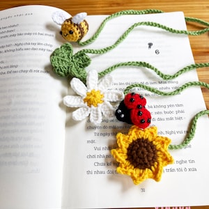 May include: A crocheted bookmark featuring a bee, a daisy, a ladybug, and a sunflower. The bookmark is made with colorful yarn and is a charming addition to any book lover's collection.