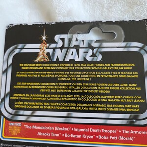 May include: Star Wars Retro Collection packaging. The black and white packaging features the Star Wars logo and text in multiple languages. The bottom of the packaging lists several character names, including "The Mandalorian (Beskar)" and "Imperial Death Trooper."