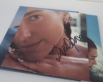 CD "Radical Optimism" di Dua Lipa, con copertina olografica e inserto autografato, confezione aperta e mai ascoltato, edizione rara da collezione Warner Records 2024.