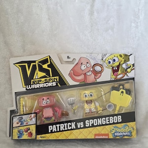 Puede incluir: Un set de juguetes Rip-Spin Warriors Patrick vs SpongeBob en su empaque original. El set incluye dos figuras pequeñas, Patricio Estrella y Bob Esponja, junto con accesorios de plástico. El cartón presenta ilustraciones de los personajes y el texto "VS RIP-SPIN WARRIORS" y "PATRICK vs SPONGEBOB".