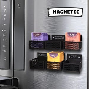 May include: Five magnetic tea bag organizers attached to a stainless steel refrigerator. Each organizer holds a stack of tea bags with different flavors and sayings. The sayings include "Blueberry Sage", "Take a moment, just for you", "Echinacea", "Warm your heart and soul", and "Keep calm, Steep on."