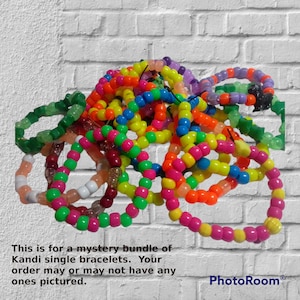 Op de afbeelding: Een stapel kleurrijke kandi-armbanden in verschillende kleuren, waaronder groen, roze, geel, oranje, blauw en paars. De armbanden zijn gemaakt van plastic kralen en zijn aan elkaar geregen op elastisch touw. Dit is voor een mystery-pakket met enkele kandi-armbanden. Uw bestelling kan de afgebeelde armbanden bevatten of niet.